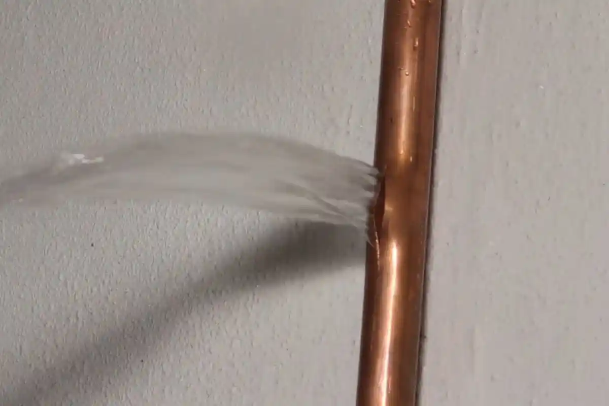 Burst copper pipe leaking water, a common winter freeze-thaw failure in Westbury, NY